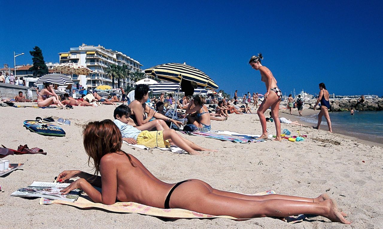 Comment voir les seins d'une fille qui bronze topless à la plage sur le ventre ?